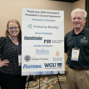 Board members smiling with sponsor sign